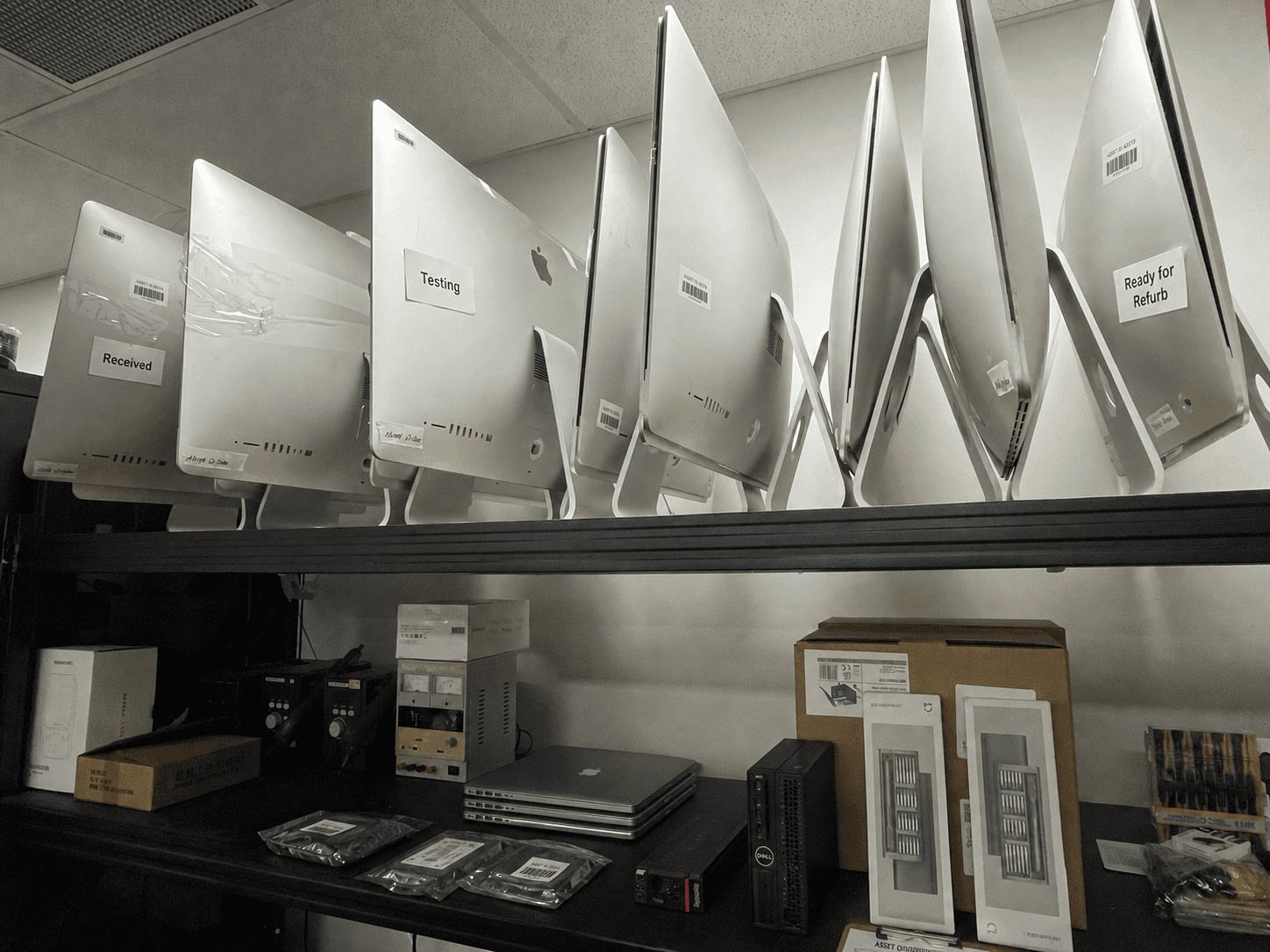 Apple desktops labelled Received, Testing, and Ready for Refurb on a workshop shelf — chain-of-custody intake for asset disposition