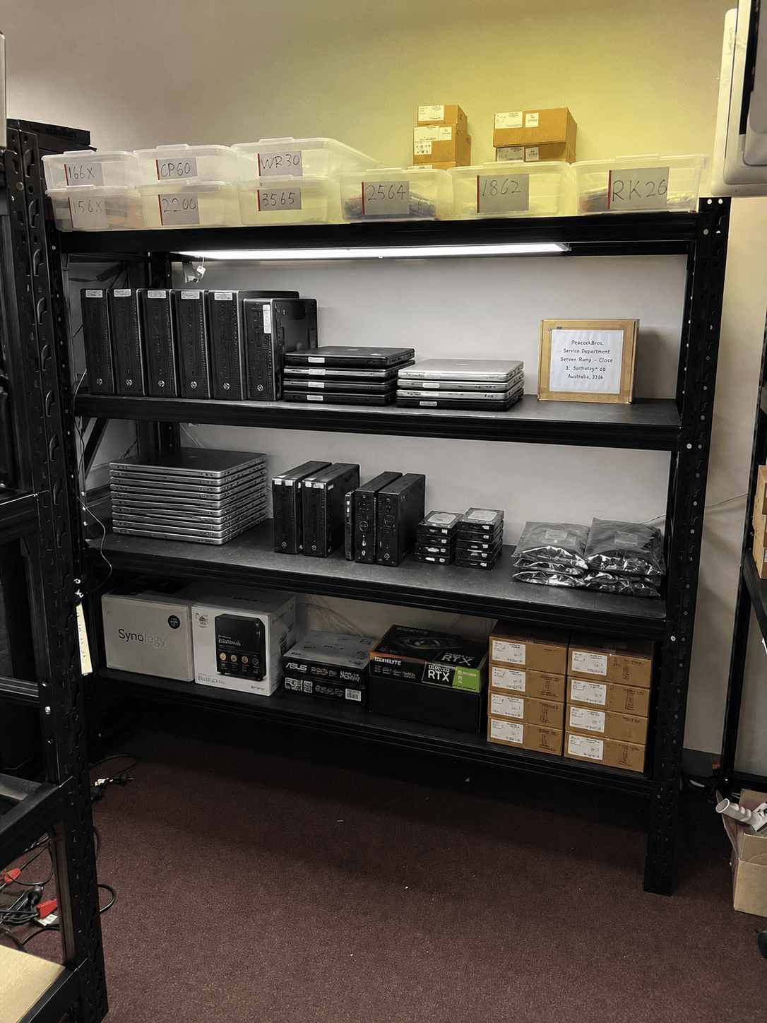 Refurbished workstations, notebooks, and components staged on the workshop inventory shelves